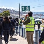 Estudiantes caminan hacia una zona de seguridad acompañados por personal de prevención y emergencias.