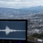 Monitor sísmico frente a una vista urbana de los cerros de Valparaíso