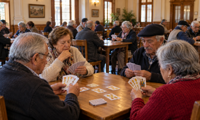 Personas mayores participan en un torneo comunitario de brisca en un salón patrimonial