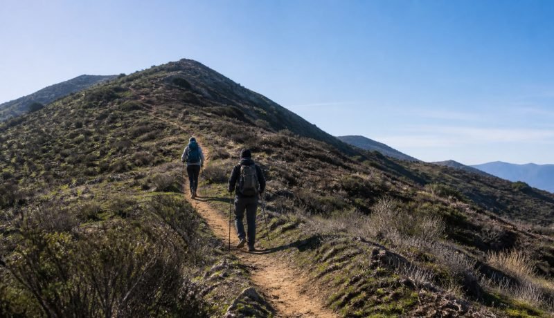 Dos excursionistas ascienden por un sendero de cerro en la zona central de Chile