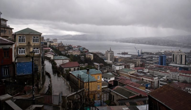 Vista de Valparaíso bajo cielo cubierto y lluvia, composición editorial referencial
