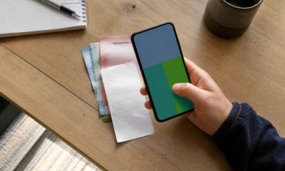 Persona revisa una transferencia en un teléfono junto a dinero y un comprobante